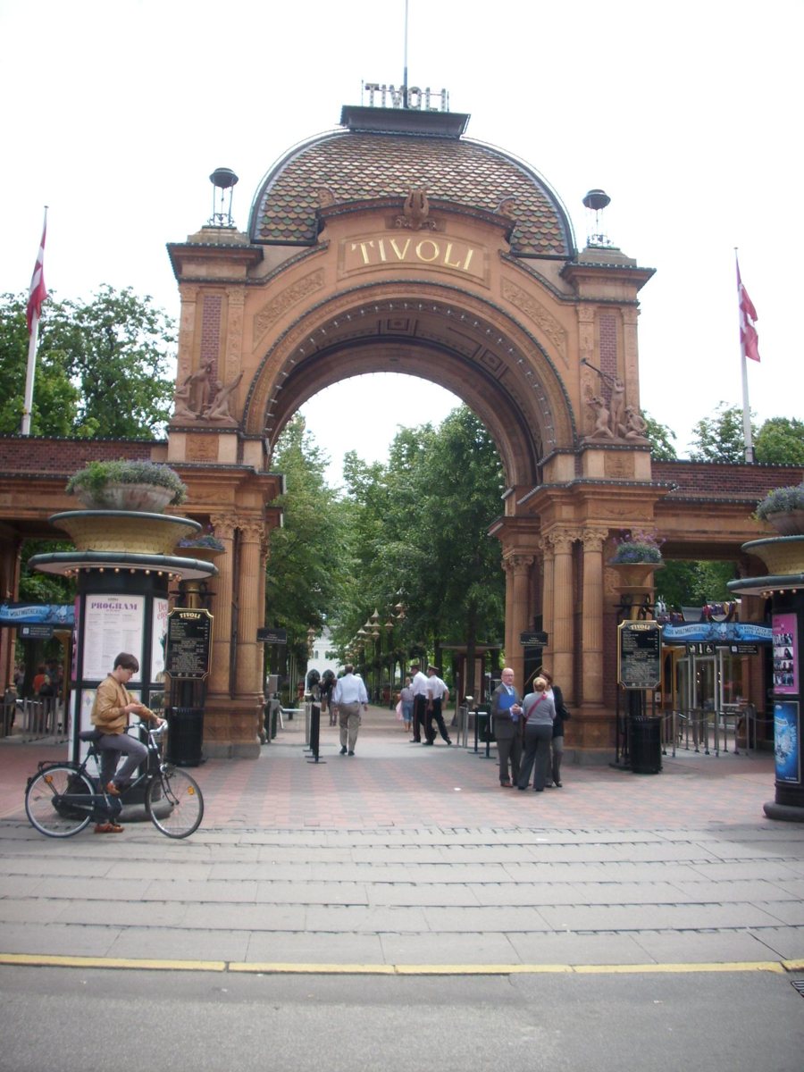 Eingangsbogen des Tivoli in Kopenhagen mit Besuchern und Radfahrer